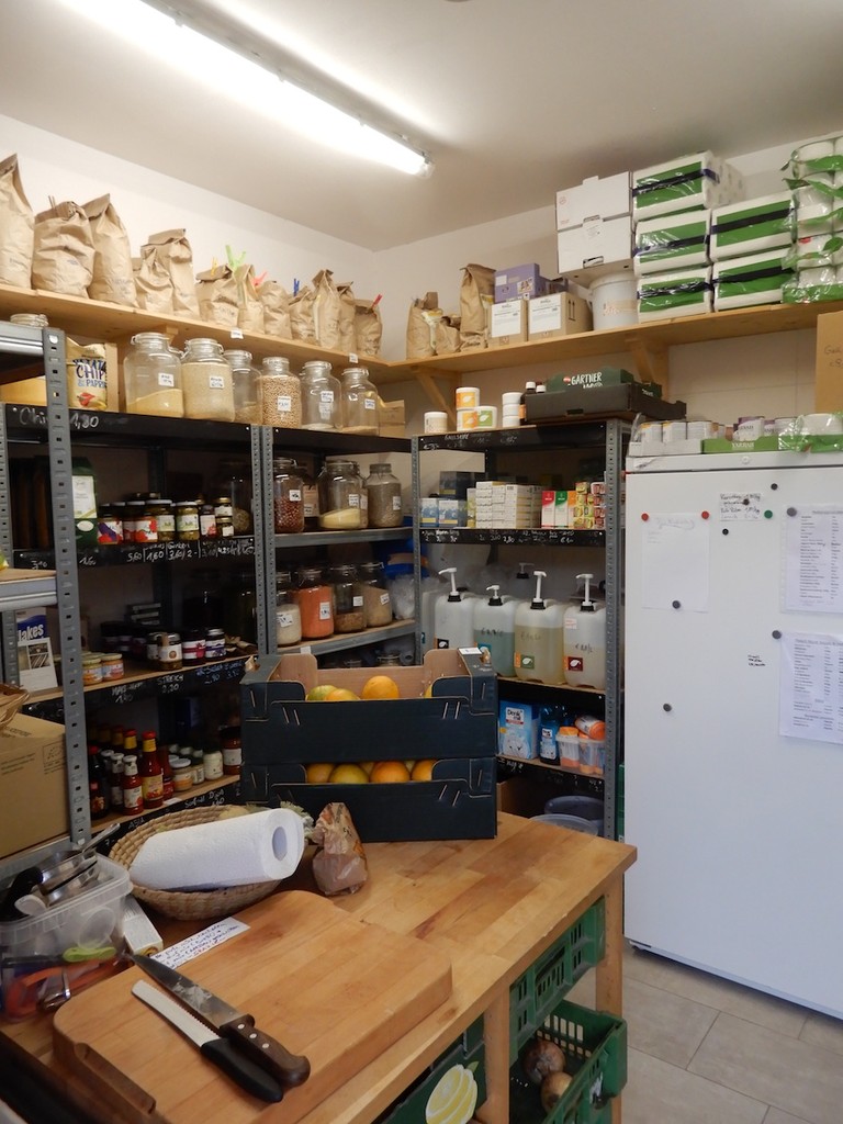 Regale mit gefüllten Gläsern, frischem Obst und Tisch mit Schneidbrett