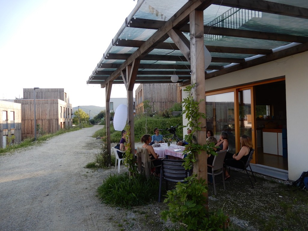 Gruppe sitzt an einem großen Tisch auf überdachter ebenerdiger Terrasse